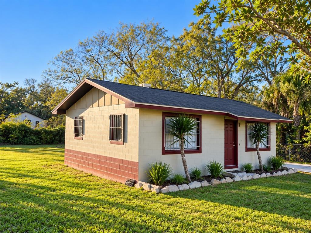 A single-story house with a maroon door and window trim viewed behind a chain-link fence — 1112/1114 S BAY AVENUE, SANFORD, FL