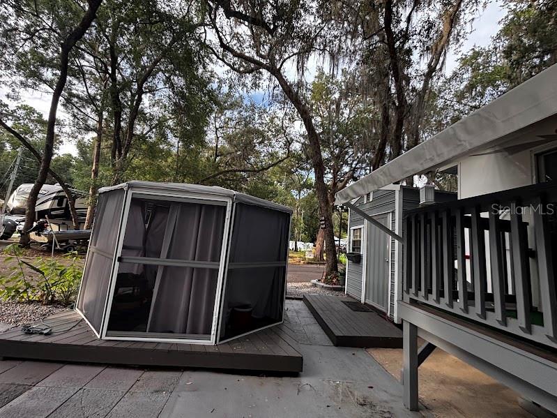 An outdoor screened gazebo sits on a wooden deck next to a small cabin structure — 25367 140TH STREET NE UNIT 315, FORT MC COY, FL