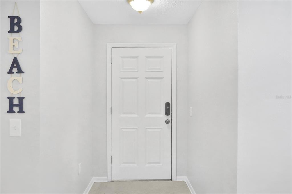 A white front door is centered in a small entryway with light-colored walls and carpet — 1004 42ND TERRACE E, BRADENTON, FL