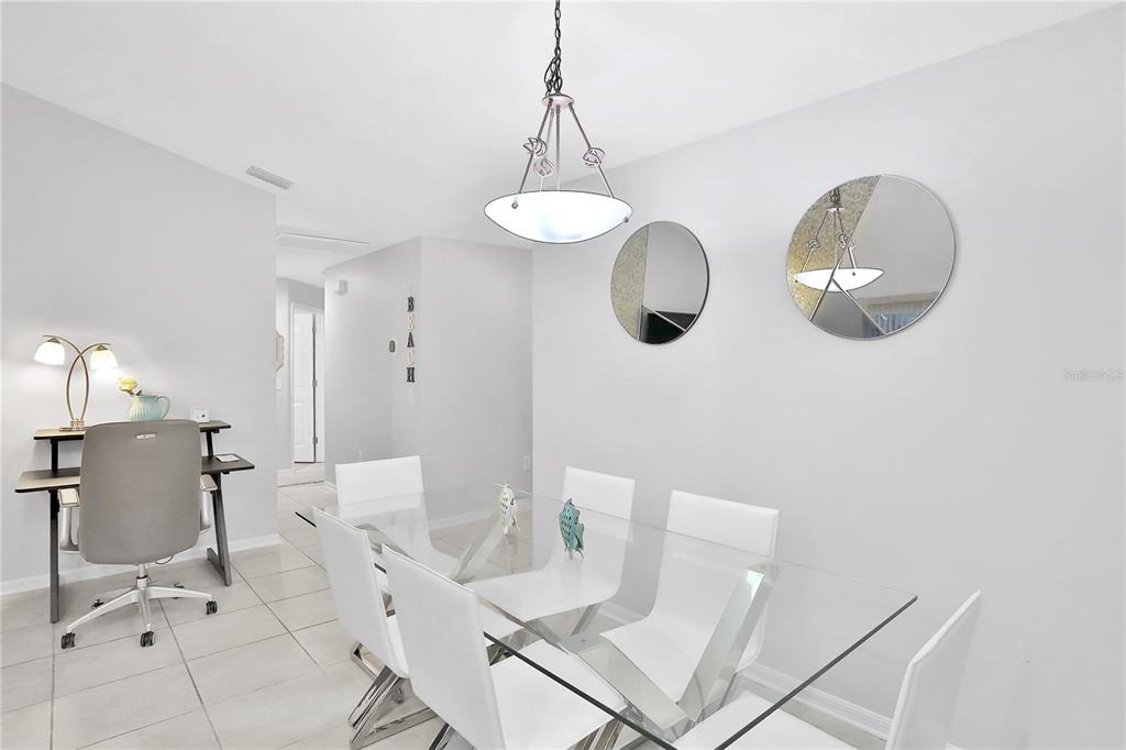 A dining room features a glass table, white chairs, two circular mirrors, and a desk — 1004 42ND TERRACE E, BRADENTON, FL