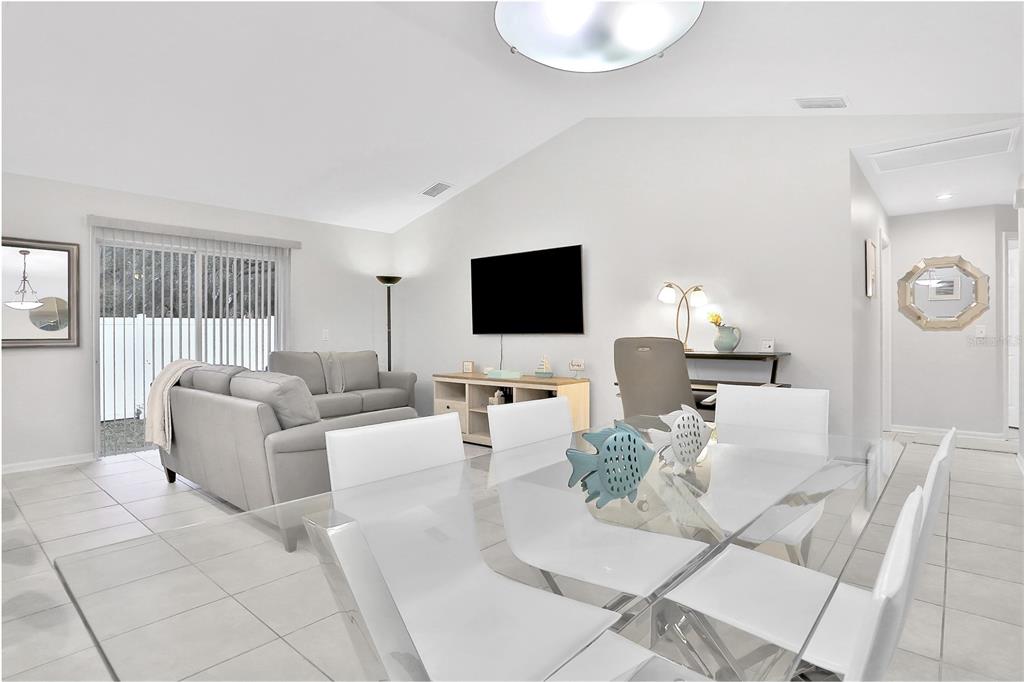 A bright living and dining area with white tile floors, a glass table, and sofa — 1004 42ND TERRACE E, BRADENTON, FL