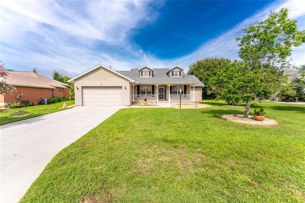 A single-story house with a beige exterior, a two-car garage, and a front porch — 7011 N PLUM TREE, PUNTA GORDA, FL