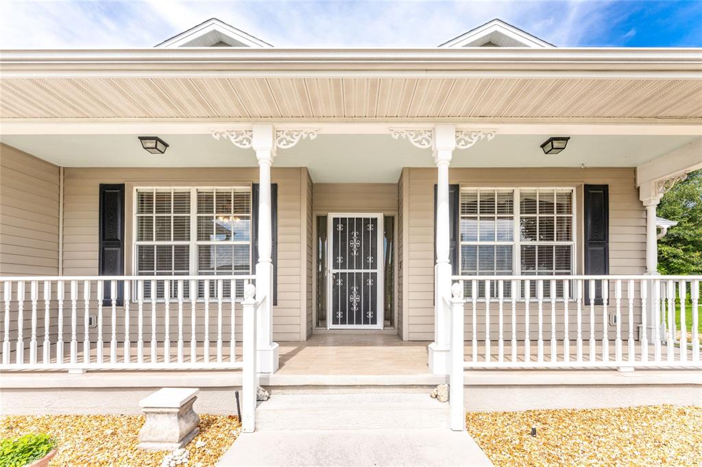 A covered front porch features white railings, decorative columns, and a central screen door — 7011 N PLUM TREE, PUNTA GORDA, FL