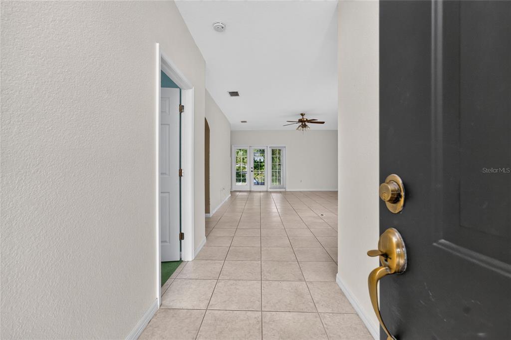 A tiled entryway leads into an open living area with a ceiling fan and glass doors — 7011 N PLUM TREE, PUNTA GORDA, FL