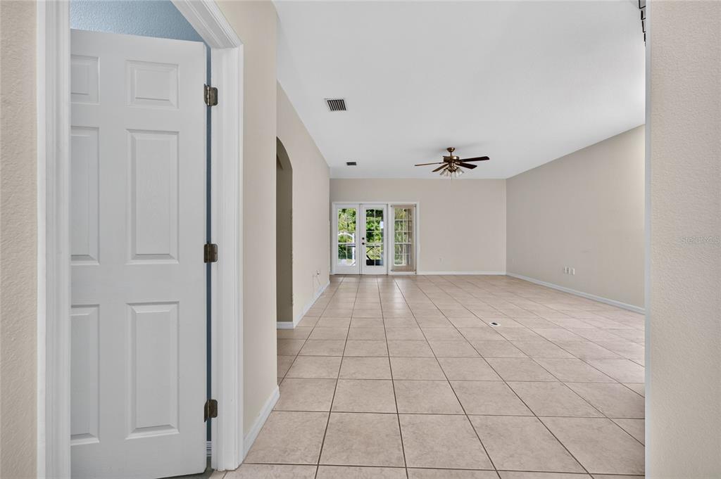 A view from a doorway into a large, tiled living area with a ceiling fan — 7011 N PLUM TREE, PUNTA GORDA, FL