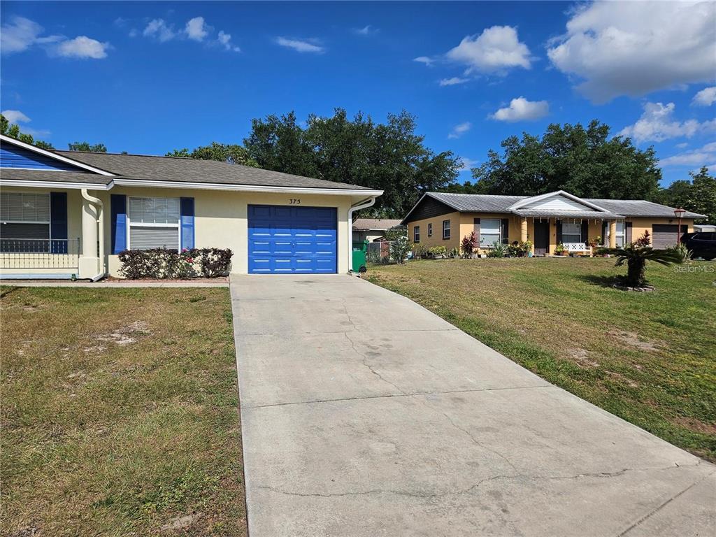 A single-story house with a blue garage door and a concrete driveway — 375 WILLOW SONG COURT, EUSTIS, FL