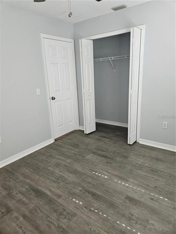 A bedroom with light gray walls, wood-look flooring, a closet, and a white interior door — 375 WILLOW SONG COURT, EUSTIS, FL