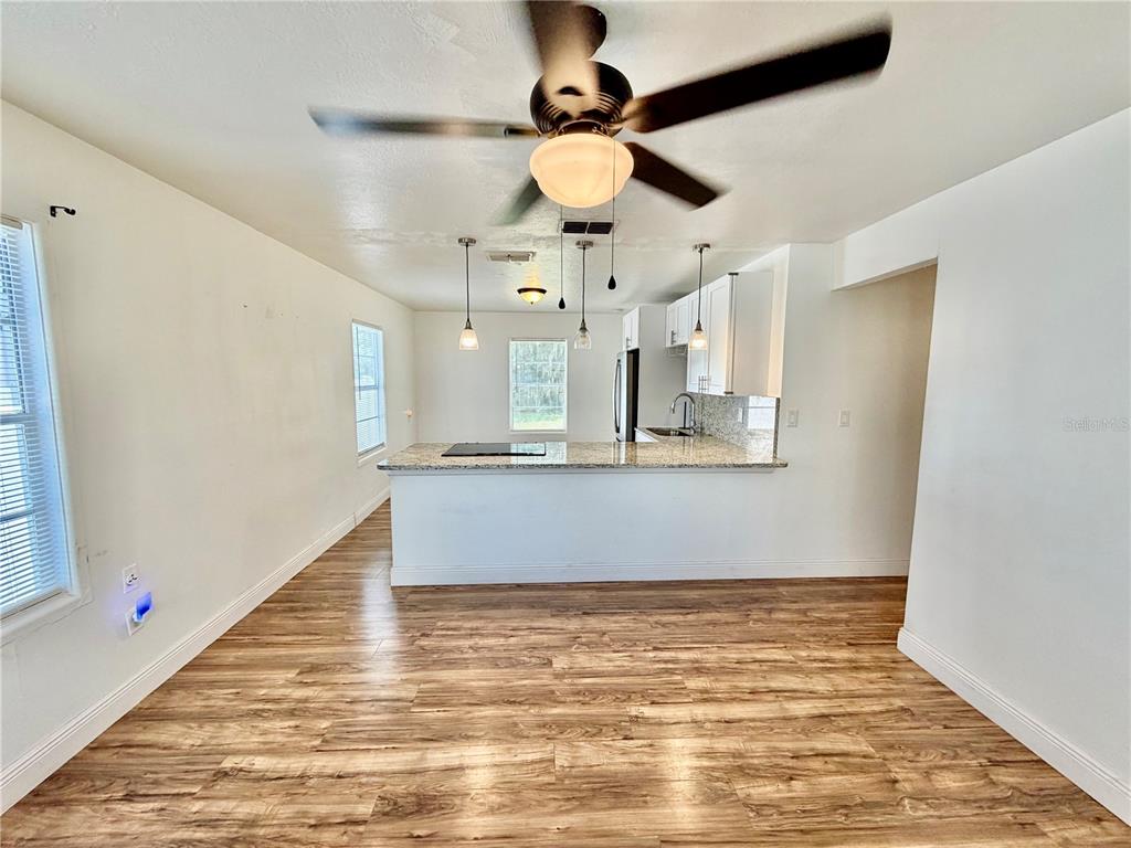 The exterior of a light-colored mobile home features a screened-in porch and two trash bins — 311 W BELLA VISTA STREET, LAKELAND, FL