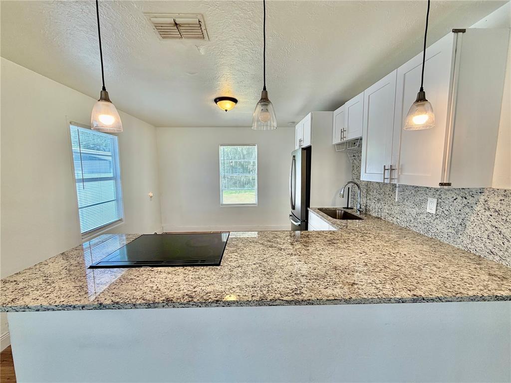 A backyard features a single-story house with light siding, a white fence, and large trees — 311 W BELLA VISTA STREET, LAKELAND, FL