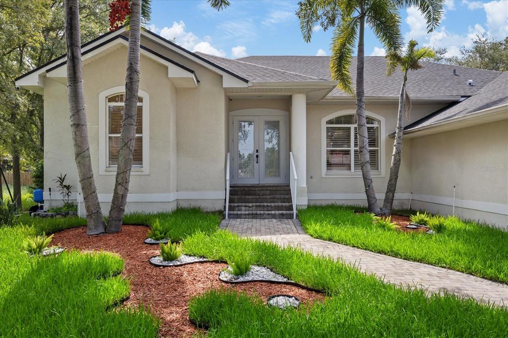 A single-story house with a beige stucco exterior, a paved walkway, and two palm trees — 2706 SKIMMER POINT DRIVE S, GULFPORT, FL