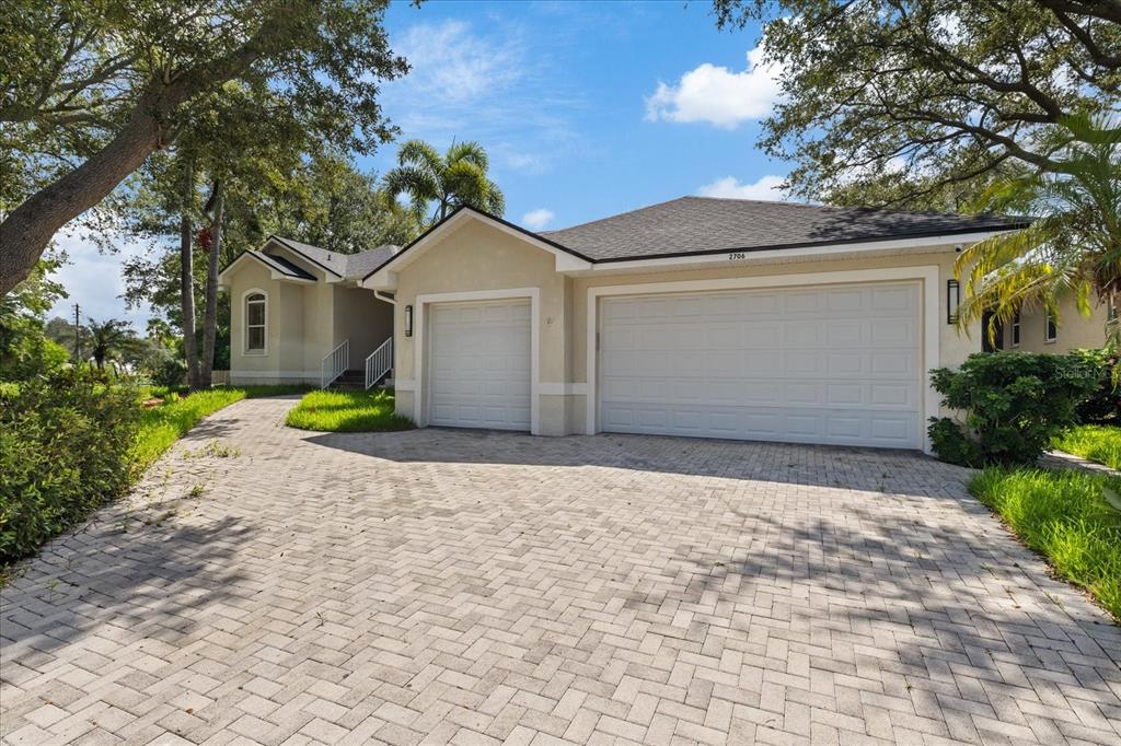 A single-story house with a paved driveway, two garage doors, and surrounding trees — 2706 SKIMMER POINT DRIVE S, GULFPORT, FL