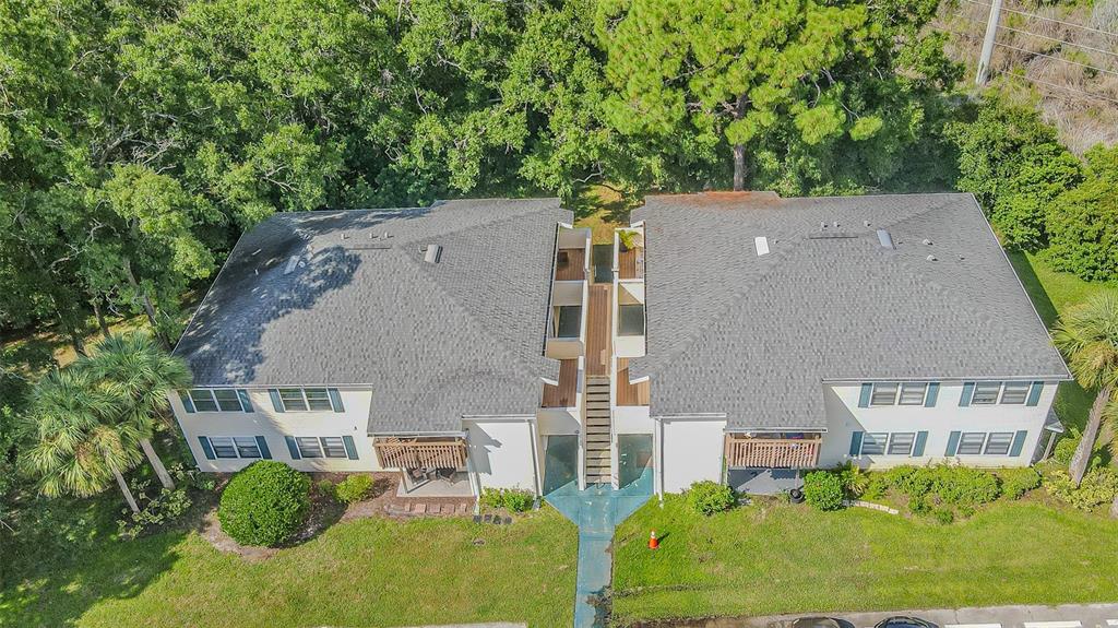 An aerial view of a two-story apartment building with a central staircase and shingled roof — 133 SABAL COURT UNIT F, OLDSMAR, FL