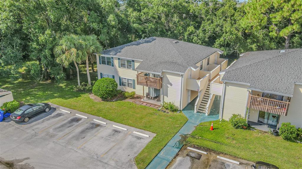 An aerial view shows two multi-story apartment buildings with parking spaces and surrounding trees — 133 SABAL COURT UNIT F, OLDSMAR, FL
