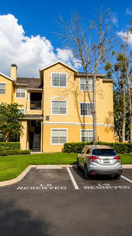 A silver SUV is parked in a reserved spot in front of a yellow apartment building — 2632 ROBERT TRENT JONES DRIVE UNIT 136, ORLANDO, FL