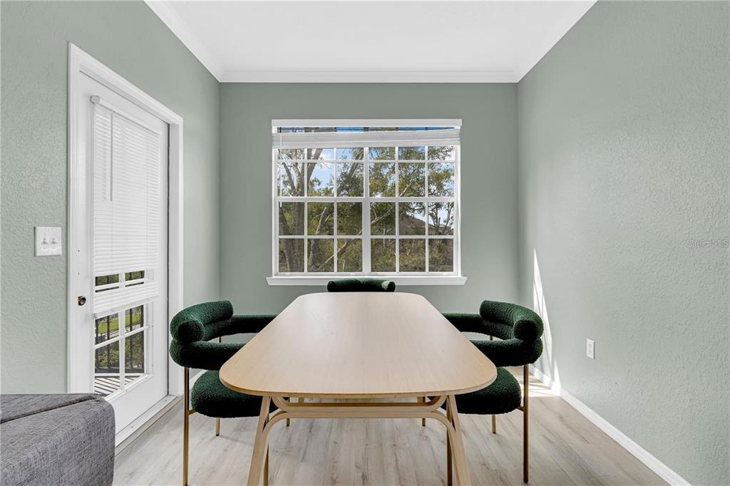 A dining room features light wood flooring, sage green walls, a window, and four green chairs — 2632 ROBERT TRENT JONES DRIVE UNIT 136, ORLANDO, FL