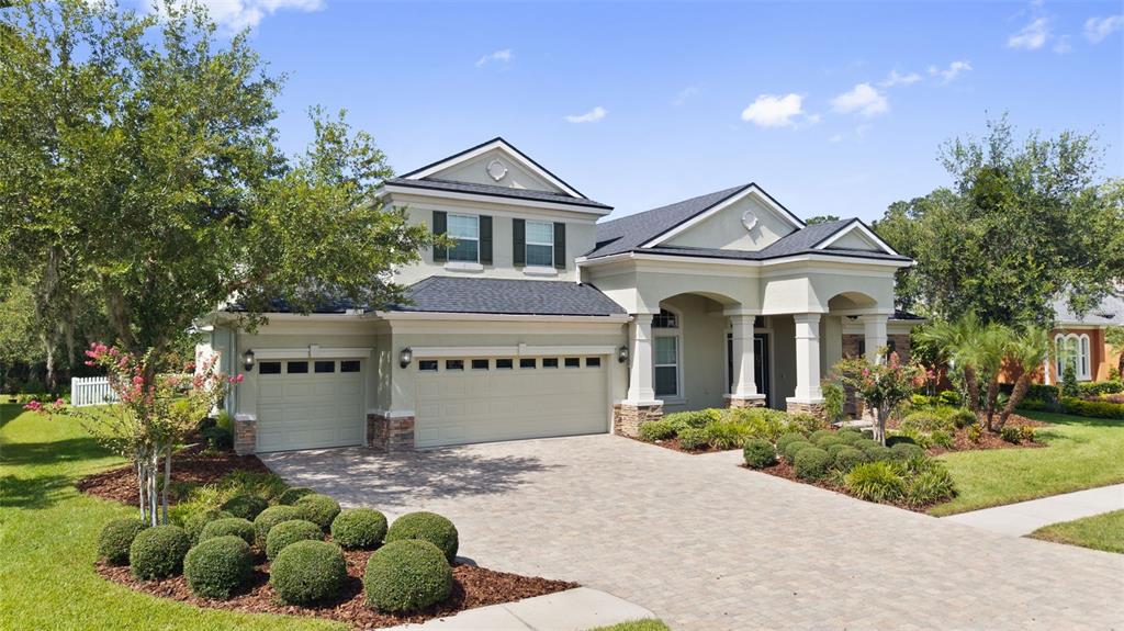 A beige two-story house with a three-car garage and a paved driveway — 27816 COBALT LANE, WESLEY CHAPEL, FL
