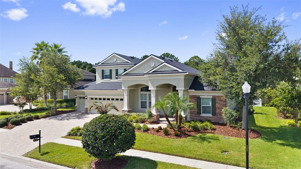 A two-story suburban house features a stone facade, arched entryway, and a paved driveway — 27816 COBALT LANE, WESLEY CHAPEL, FL