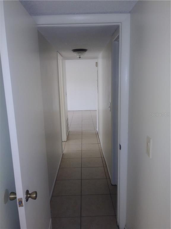 A narrow hallway with light-colored tile flooring leads to an open room beyond — 902 LAKE DESTINY ROAD UNIT B, ALTAMONTE SPRINGS, FL