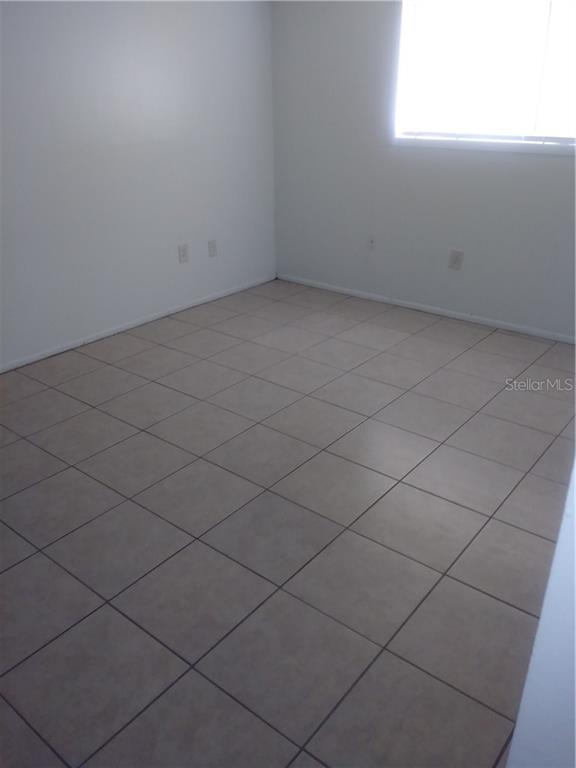 An empty room features white walls, a single window, and light-colored square floor tiles — 902 LAKE DESTINY ROAD UNIT B, ALTAMONTE SPRINGS, FL