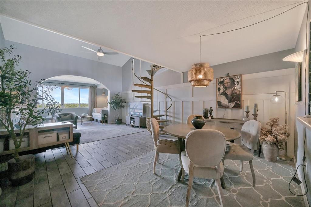A dining area with a spiral staircase leads to an arched living room with tile floors — 9604 CORTEZ ROAD W UNIT 334, BRADENTON, FL