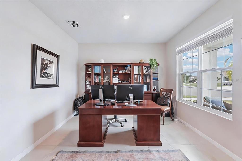 A home office features a large wooden desk, dual monitors, and a built-in bookshelf — 13055 WILLOW GROVE DRIVE, RIVERVIEW, FL
