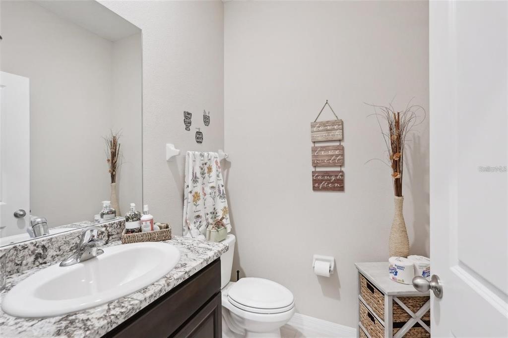 A bathroom features a granite vanity, a white toilet, and a wall-mounted decorative wooden sign — 13055 WILLOW GROVE DRIVE, RIVERVIEW, FL