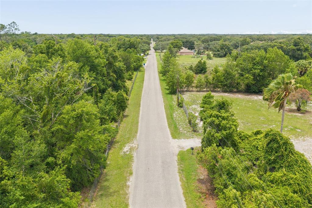 An aerial view shows a paved road stretching through a rural area with surrounding trees — 9345 ORCHARD WAY, SPRING HILL, FL
