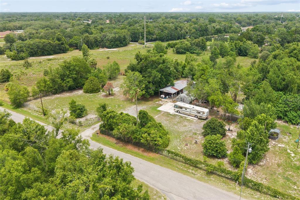 An aerial view shows a rural property with a house, a parked RV, and trees — 9345 ORCHARD WAY, SPRING HILL, FL