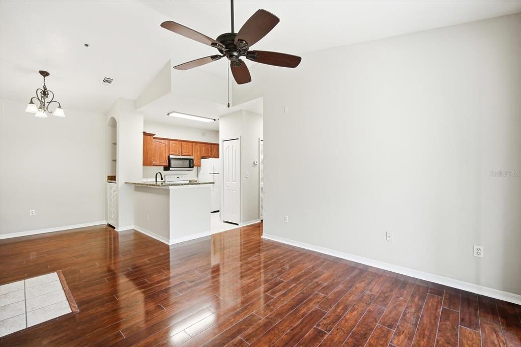 An open-concept living and dining area features dark wood flooring, a ceiling fan, and kitchen — 5703 LEGACY CRESCENT PLACE UNIT 301, RIVERVIEW, FL