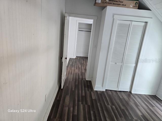 A room with wood-look flooring, white walls, a louvered closet door, and an open doorway — 7306 EARLWOOD AVENUE UNIT 5, MOUNT DORA, FL