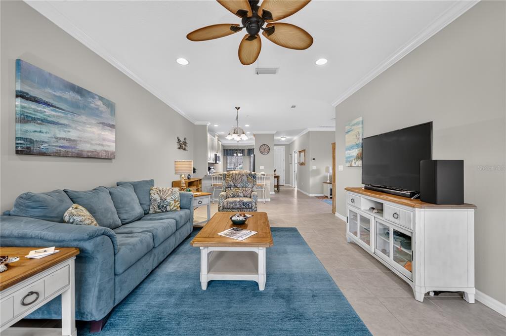 A living room features a blue sofa, a wooden coffee table, and a television console — 12710 SORRENTO WAY UNIT 101, BRADENTON, FL