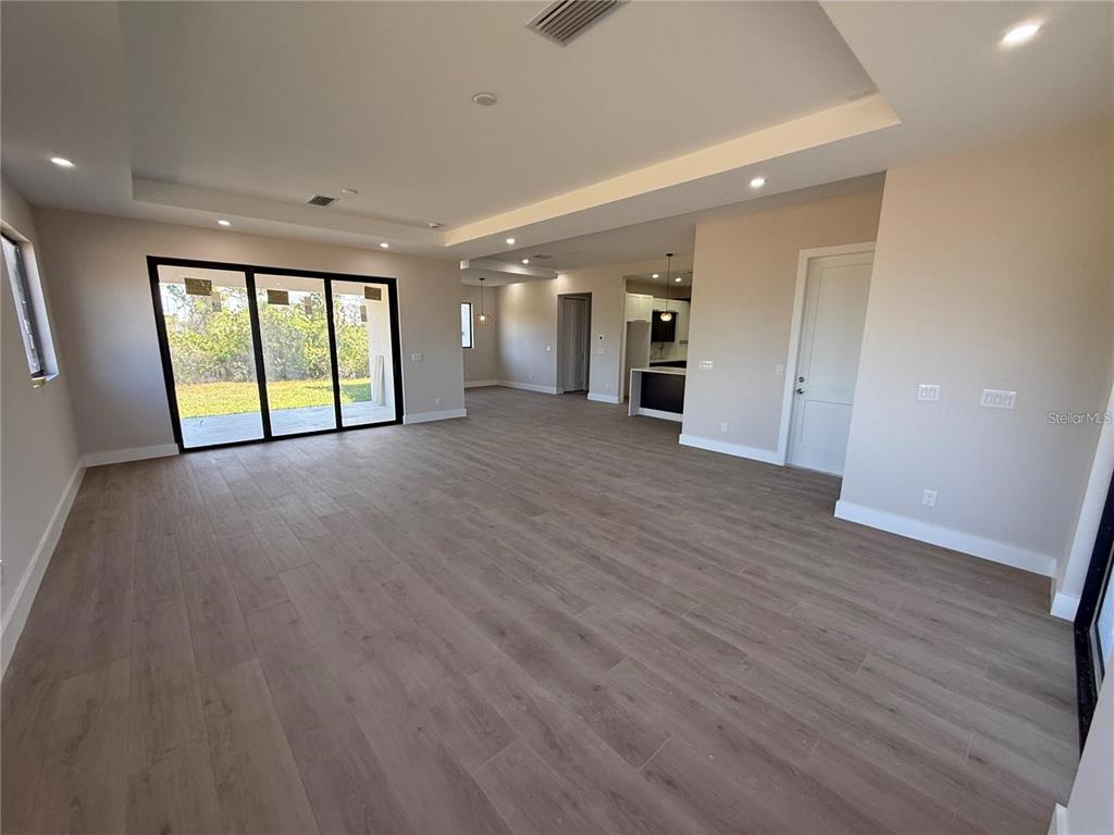 An open-concept living area features light wood-look flooring, recessed lighting, and sliding glass doors — 47 BRIG CIRCLE E, PLACIDA, FL