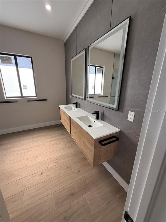 A modern bathroom features a floating wood vanity, dual sinks, and large rectangular mirrors — 47 BRIG CIRCLE E, PLACIDA, FL