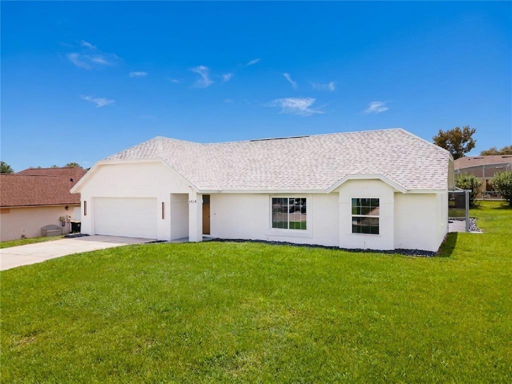 A single-story white house with a two-car garage and a large front lawn — 5424 LOMA VISTA DRIVE E, DAVENPORT, FL