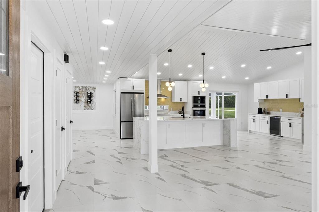 A bright, open-concept kitchen features white cabinetry, marble-patterned tile floors, and a large center island — 5424 LOMA VISTA DRIVE E, DAVENPORT, FL