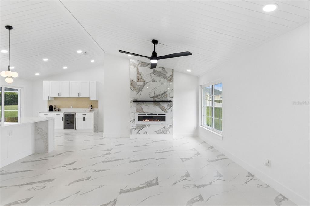 A bright living room features white marble floors, a fireplace with marble surround, and a ceiling fan — 5424 LOMA VISTA DRIVE E, DAVENPORT, FL