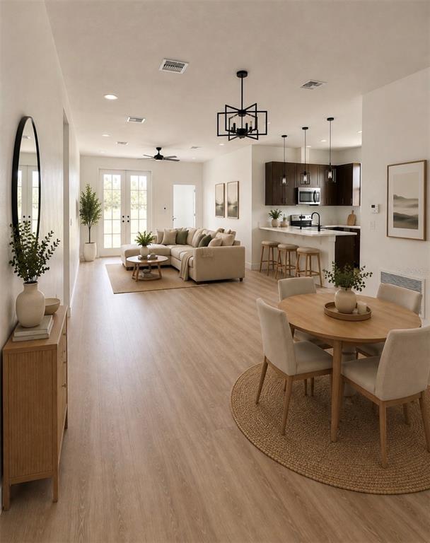 An open-concept living and dining area features light wood flooring, neutral furniture, and dark cabinetry — 5541 MOONGATE ROAD, SPRING HILL, FL