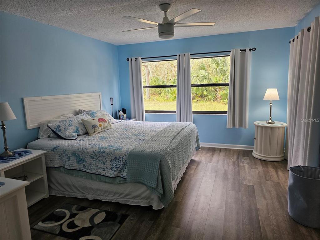 A walk-in closet features a central white shelving unit, hanging clothes, and storage bins — 2104 GRANADA COURT, LAKE WALES, FL