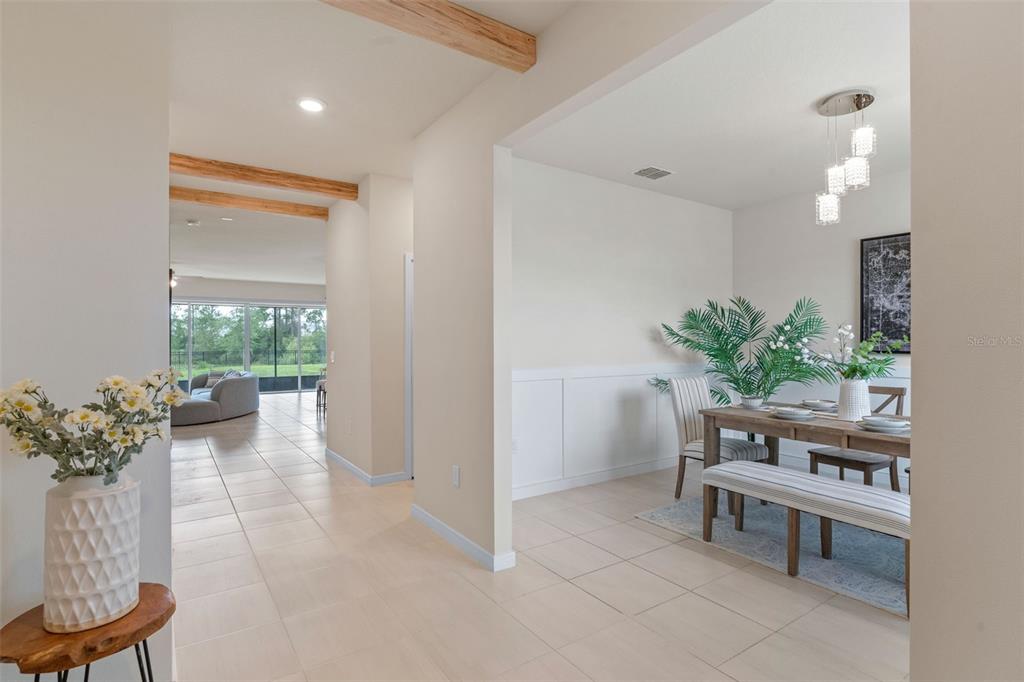 A dining area with a wooden table and bench sits beside a tiled hallway — 17319 MILLION LAKES COURT, CLERMONT, FL