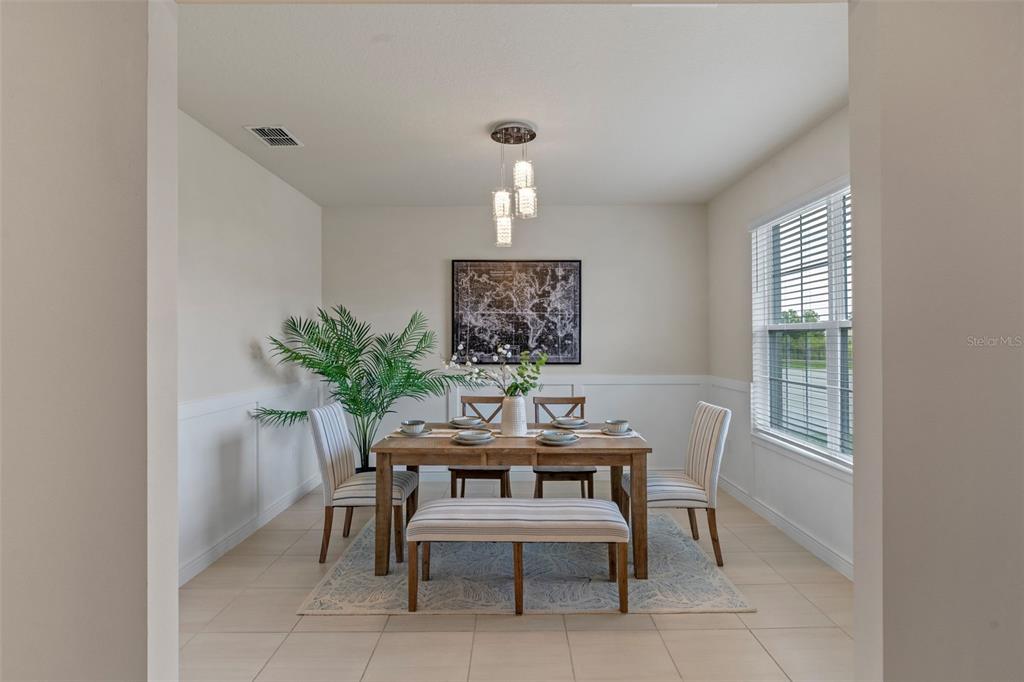 A dining room features a wooden table, striped chairs, a bench, and a pendant light — 17319 MILLION LAKES COURT, CLERMONT, FL