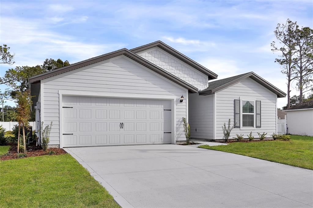 A single-story house with white horizontal siding, a two-car garage, and a concrete driveway — 19 PINEAPPLE DRIVE, PALM COAST, FL