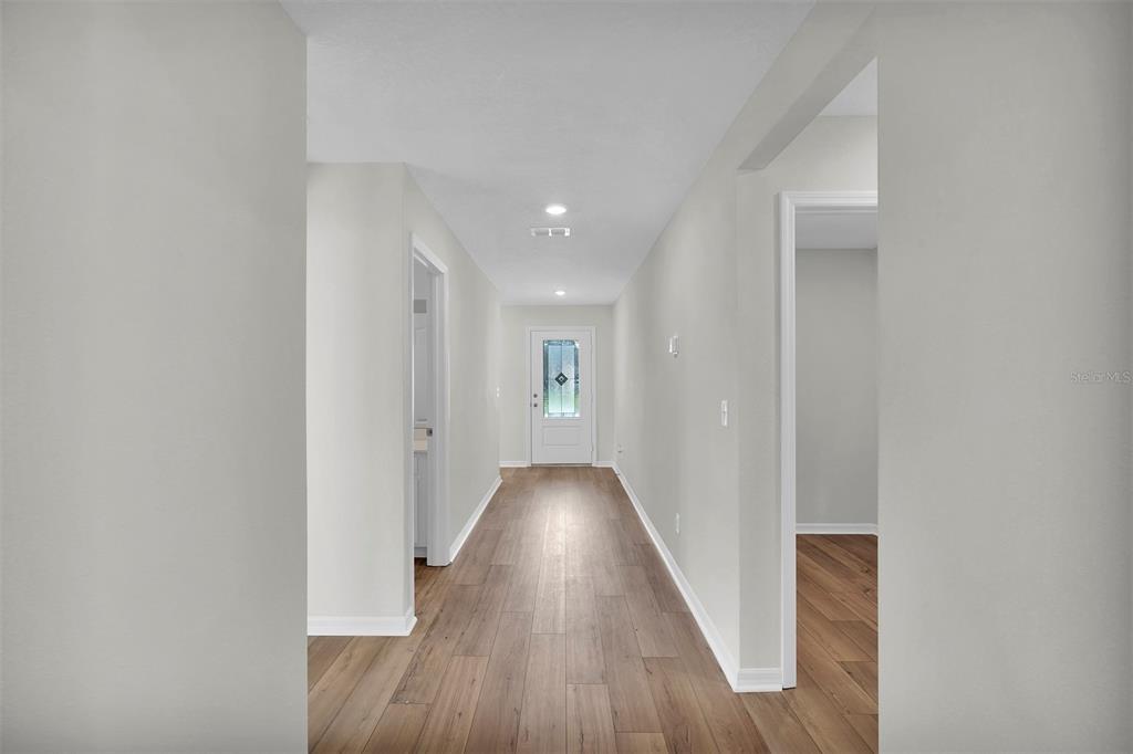 A hallway with light gray walls, wood-look flooring, and a white front door — 19 PINEAPPLE DRIVE, PALM COAST, FL