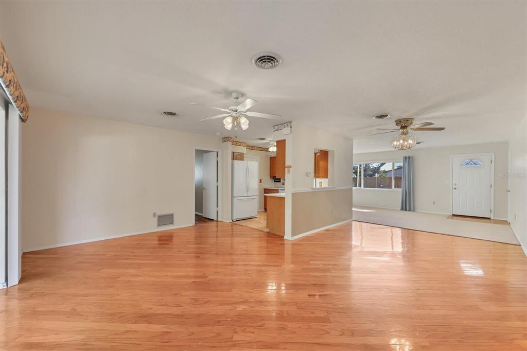 A spacious living room with hardwood floors, a ceiling fan, and an open kitchen area — 1120 GRAHAM ROAD, VENICE, FL