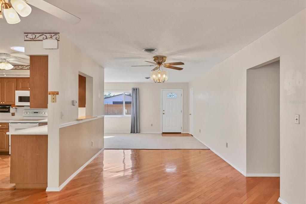 A view from a hardwood-floored dining area toward a carpeted living room and front door — 1120 GRAHAM ROAD, VENICE, FL