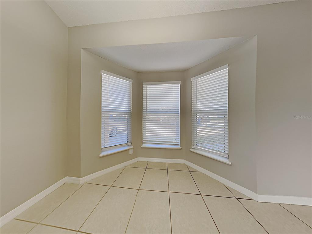 A room with light-colored tile flooring and a bay window featuring white horizontal blinds — 1322 DRAGON HEAD DRIVE, VALRICO, FL