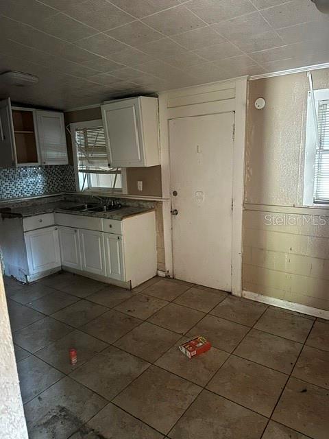A kitchen features white cabinets, tiled countertops, a tiled backsplash, and light-colored floor tiles — 3915 AVENUE Q NW, WINTER HAVEN, FL