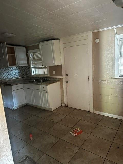 A kitchen features white cabinets, a tiled backsplash, and light-colored floor tiles — 3915 AVENUE Q NW, WINTER HAVEN, FL