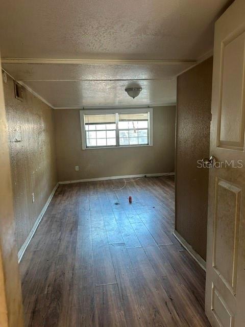 An empty room features wood-look flooring, beige walls, and a window centered on the back wall — 3915 AVENUE Q NW, WINTER HAVEN, FL