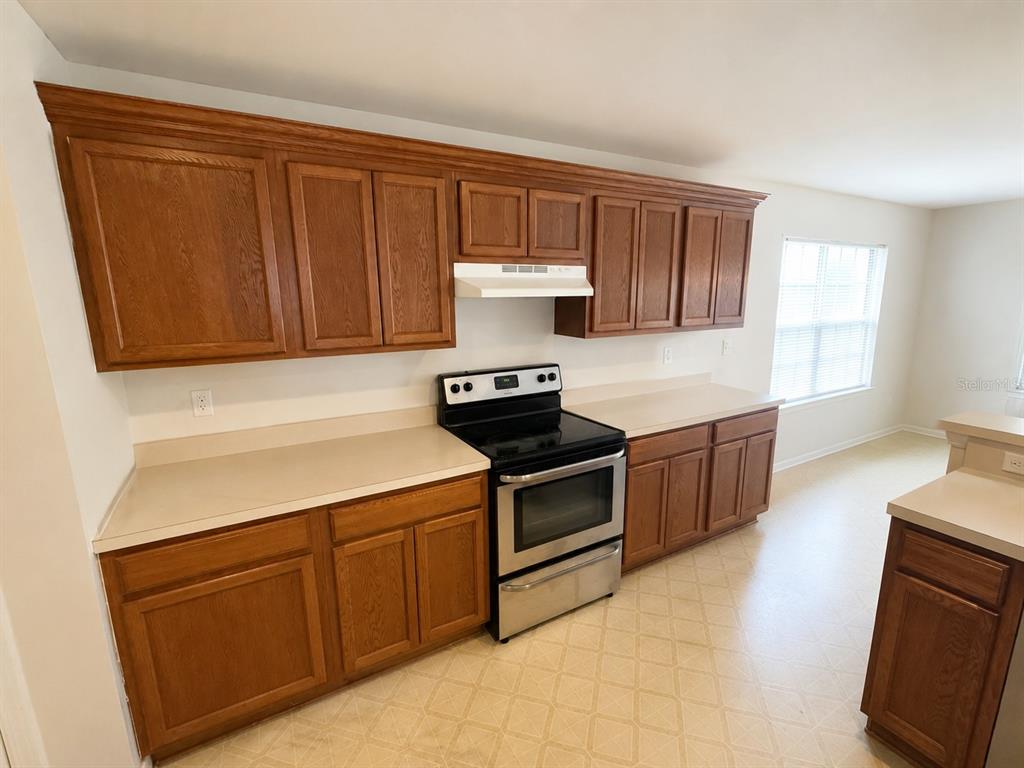 A kitchen features oak cabinets, laminate countertops, and a stainless steel stove — 21468 DAWSON AVENUE, PORT CHARLOTTE, FL