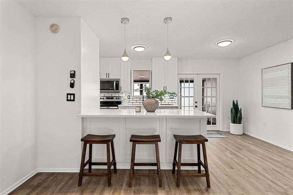 A kitchen features a white island with three wooden stools, white cabinetry, and light flooring — 11917 CONGRESSIONAL DRIVE, TAMPA, FL